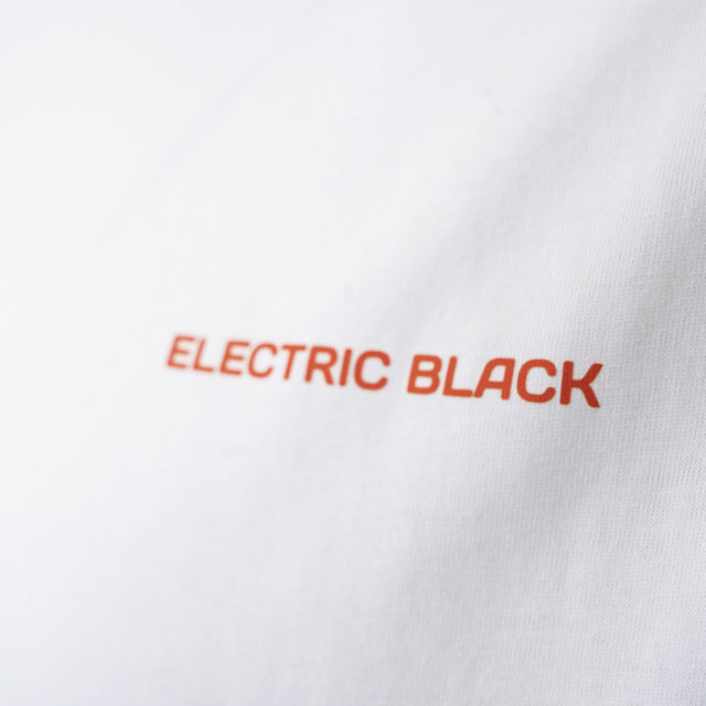 Close-up of the white Electric Black t-shirt with the logo written in orange.